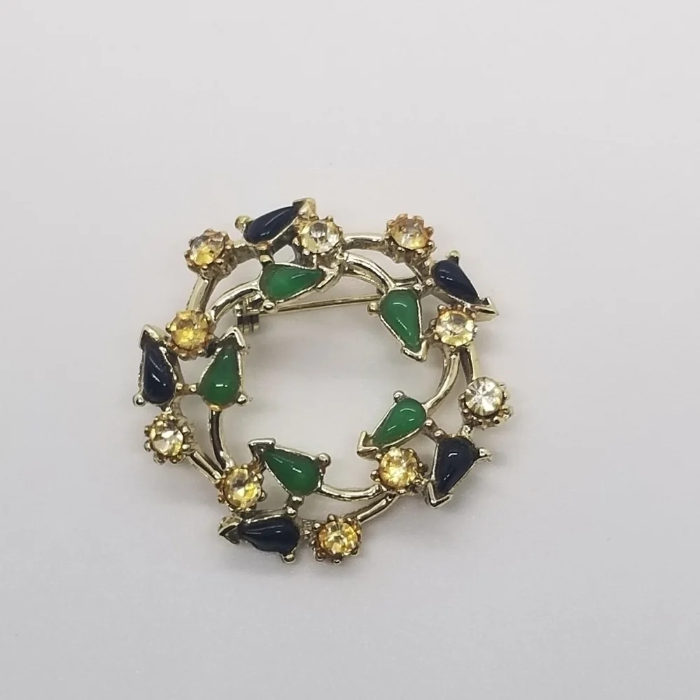 gold tone wreath brooch with clear green and black accents